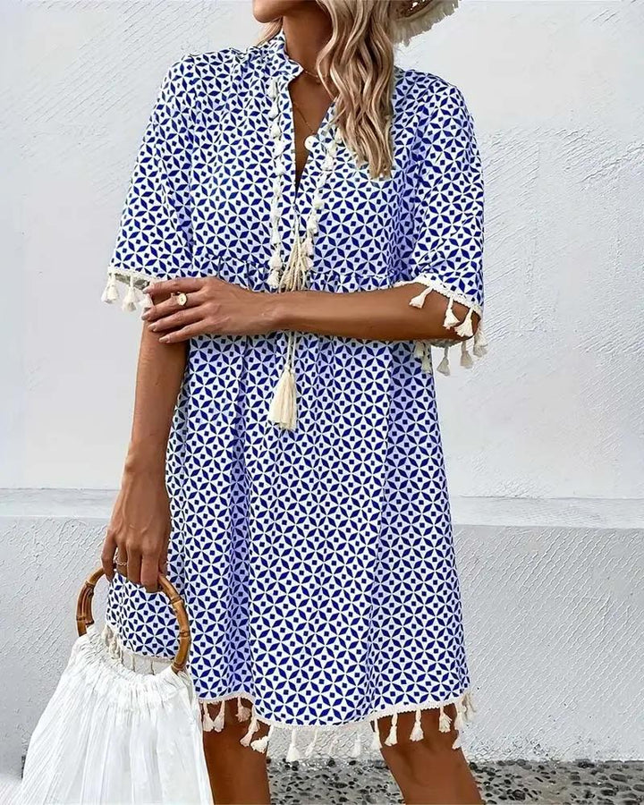 Casual women's short sleeve mini dress with a vibrant print, V-neck, and fashionable tassel trim. Summer style.