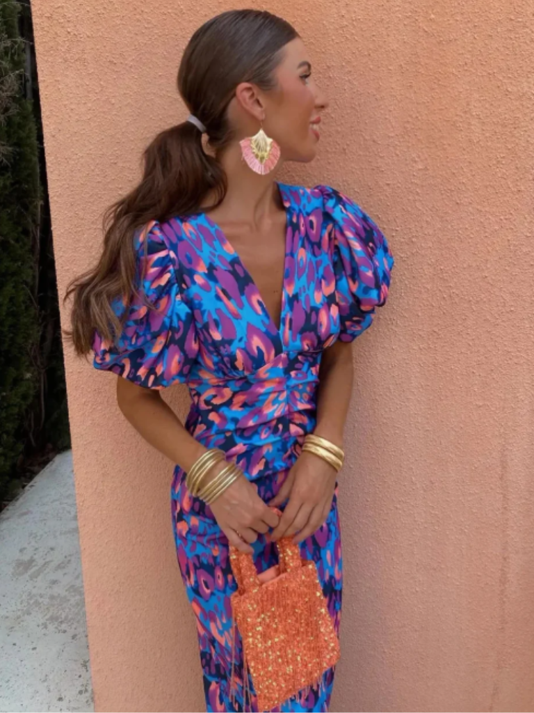 Women's elegant ruched midi dress in a vivid, vibrant abstract print. Chic party and occasion wear.