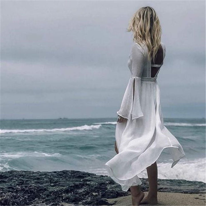 Women's white summer maxi dress with a captivating open back and stylish flare sleeves, ideal for the beach.
